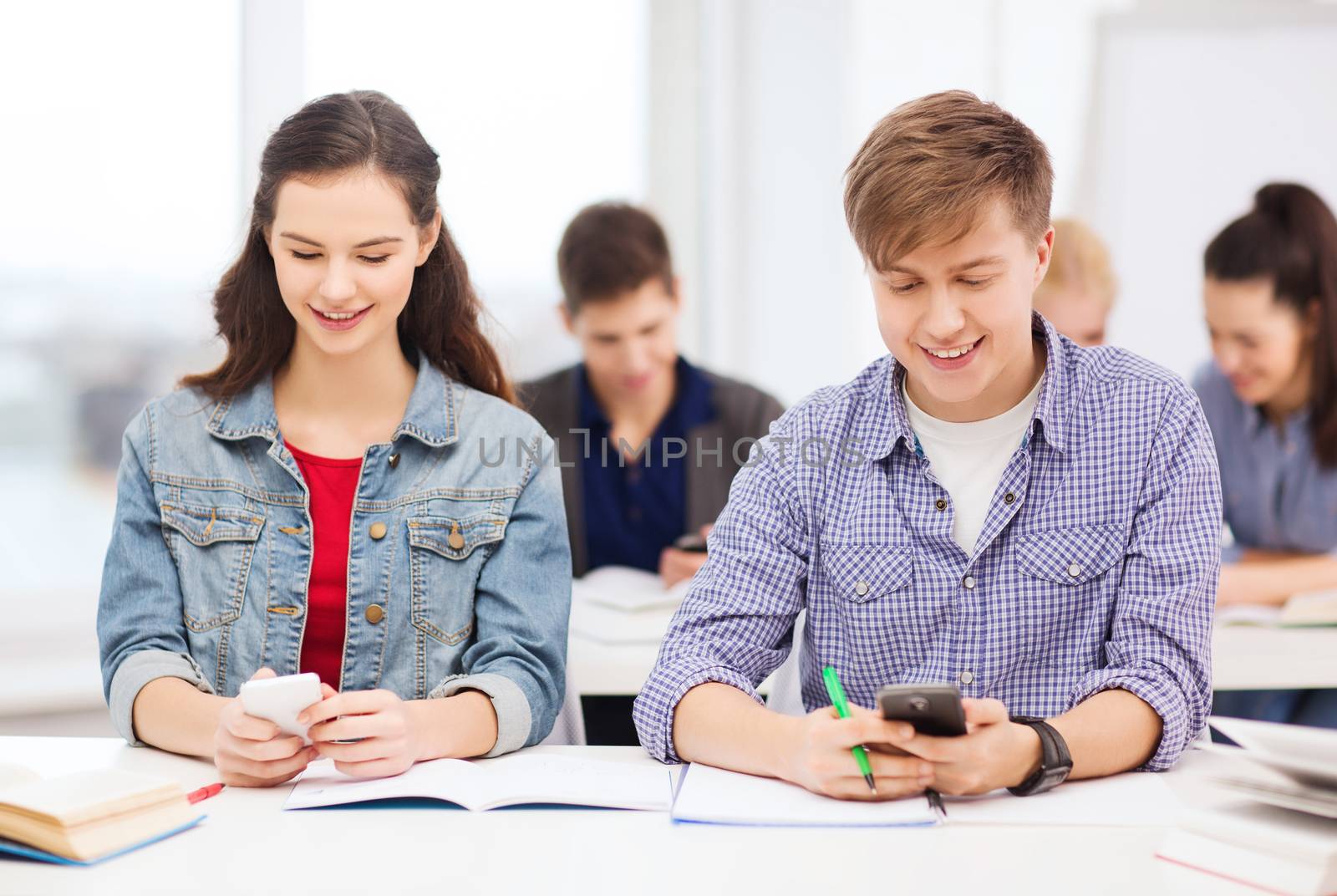 education and technology concept - group of students looking into smartphone at school