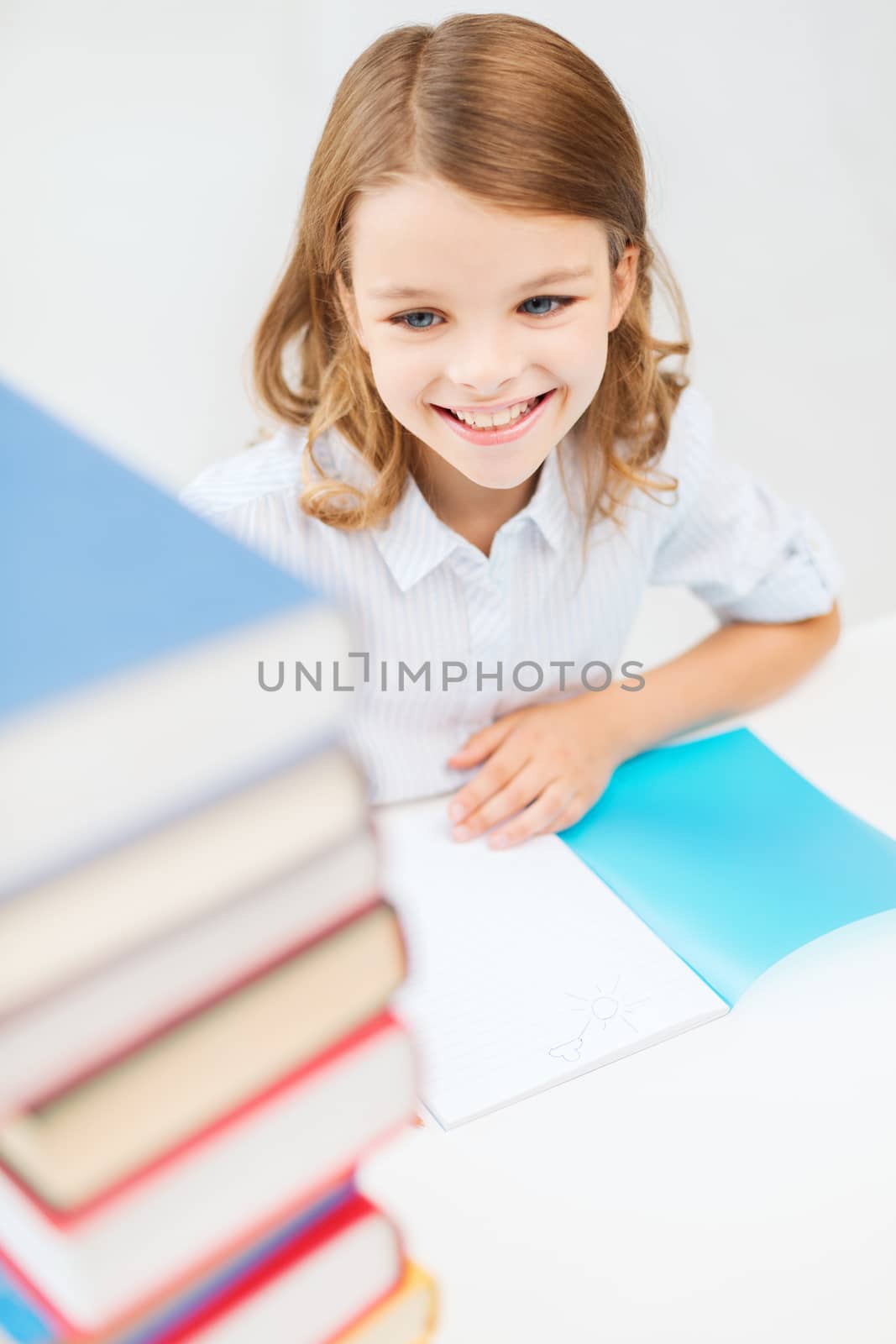 education and school concept - smiling little student girl with many books at school