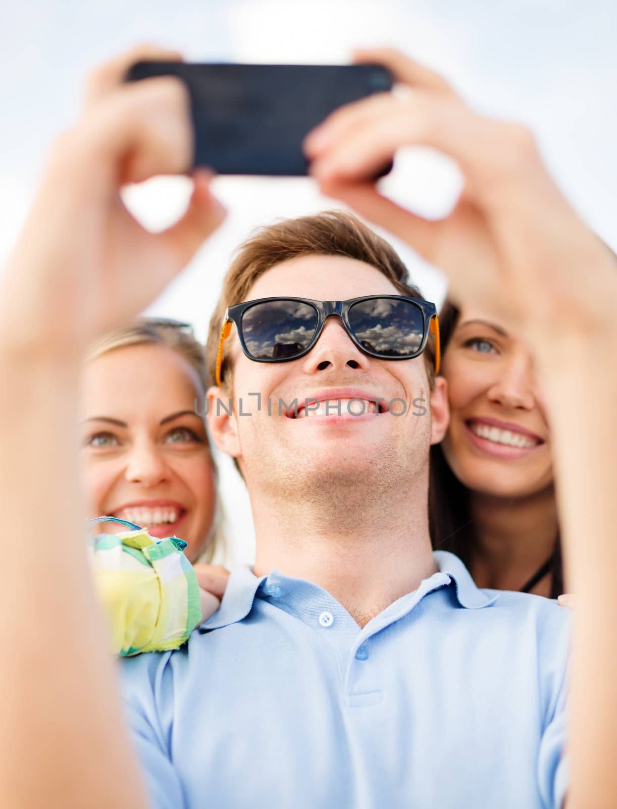 summer, holidays, vacation and happiness concept - group of friends taking picture with smartphone