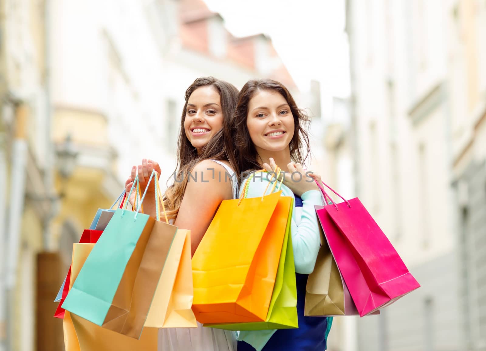 sale, shopping, tourism and happy people concept - two beautiful women with shopping bags in the ctiy