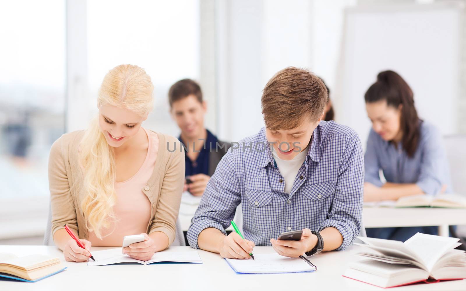 education and technology concept - group of students looking into smartphone at school