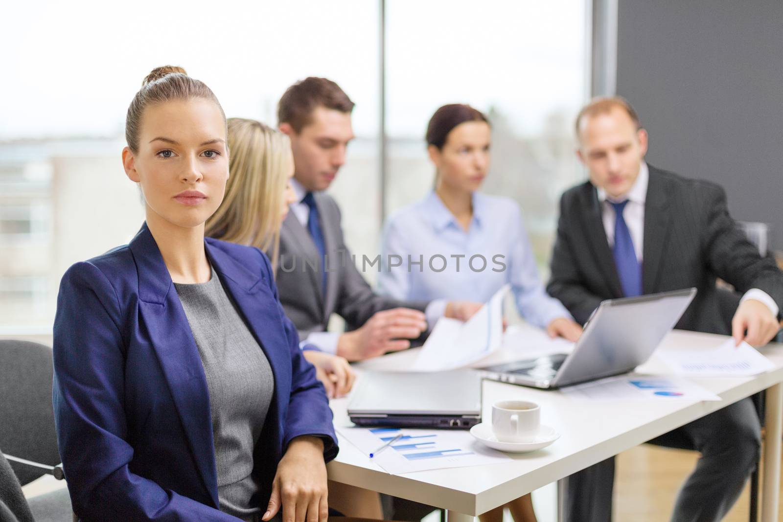 business, technology and office concept - smiling businesswoman in office with team on the back