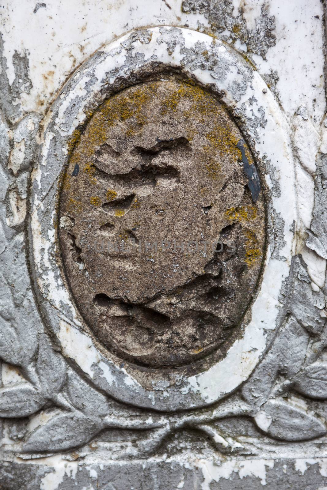 Old gravestone with damaged portrait of the buried person.
