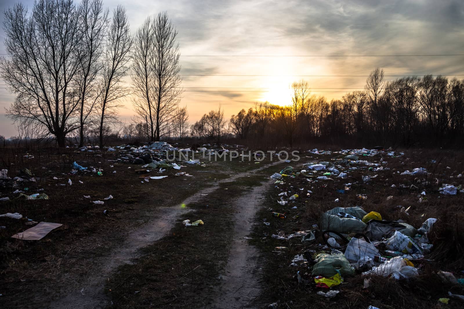 Piles of garbage near the dirt road with sunset background