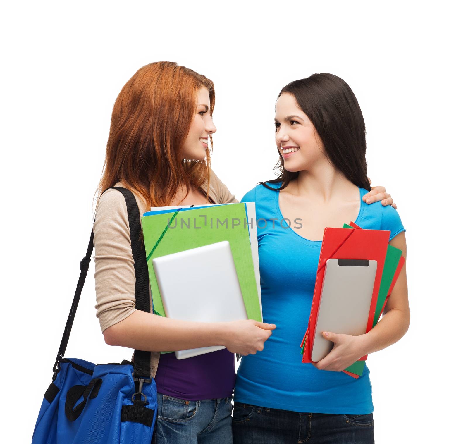 education and people concept - two smiling students with bag and folders standing looking at each other