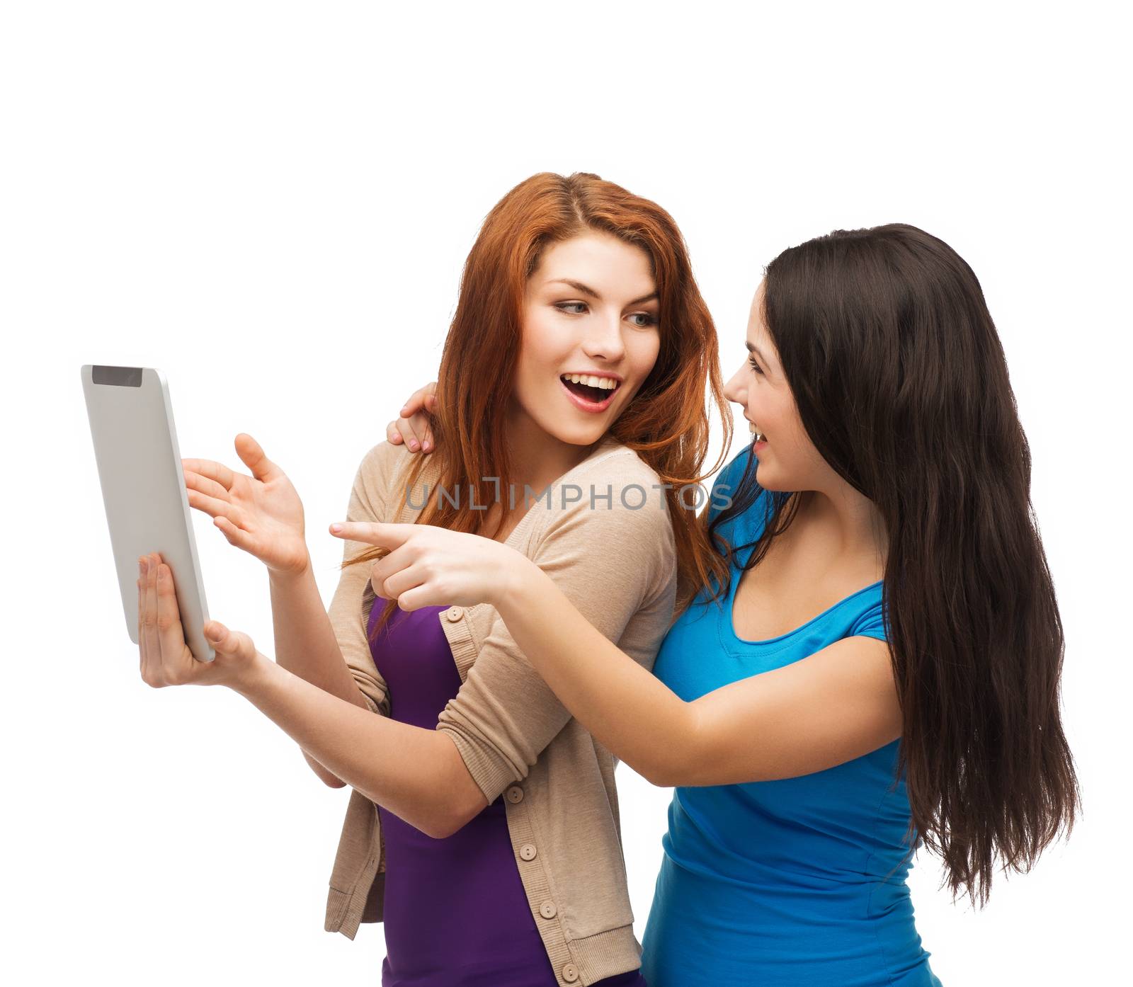 technology, friendship and people concept - two smiling teenagers pointing finger at tablet pc screen