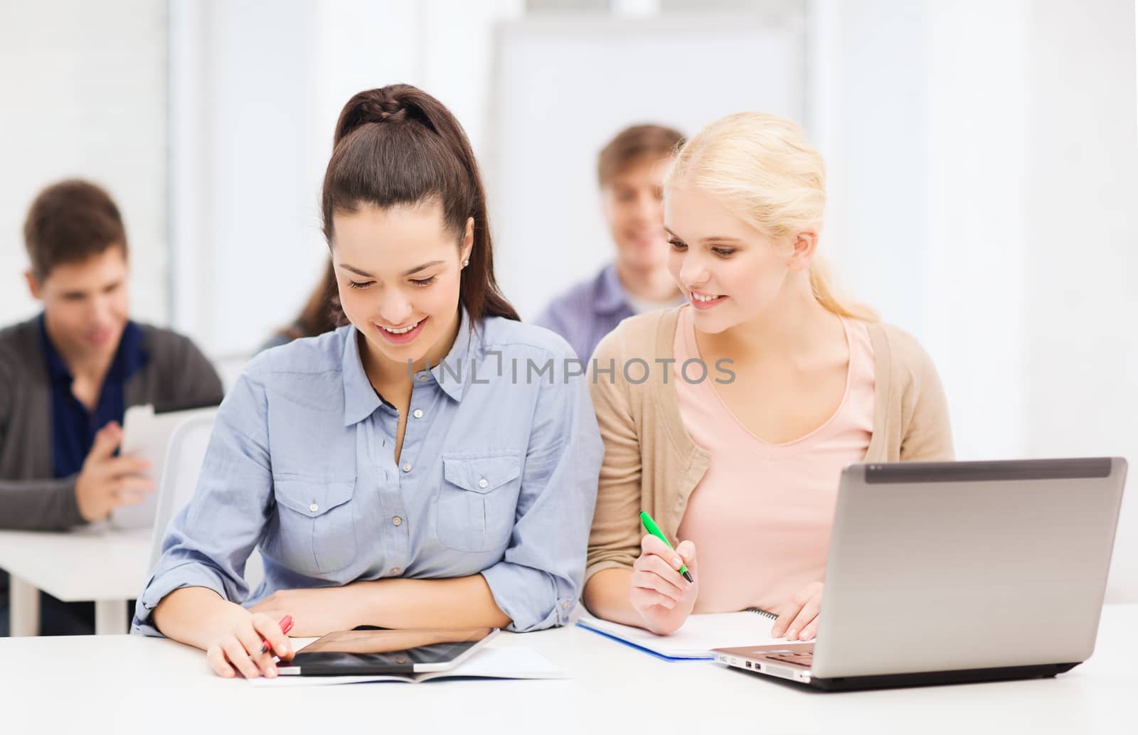 two smiling students with laptop and tablet pc by dolgachov
