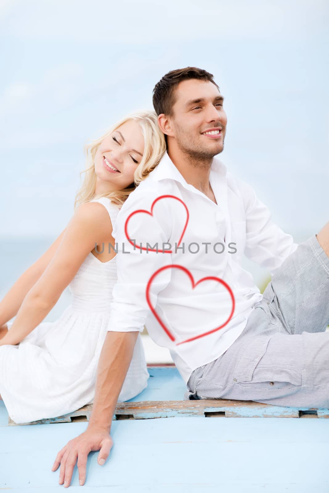 summer holidays and dating concept - couple sitting on boat at sea side