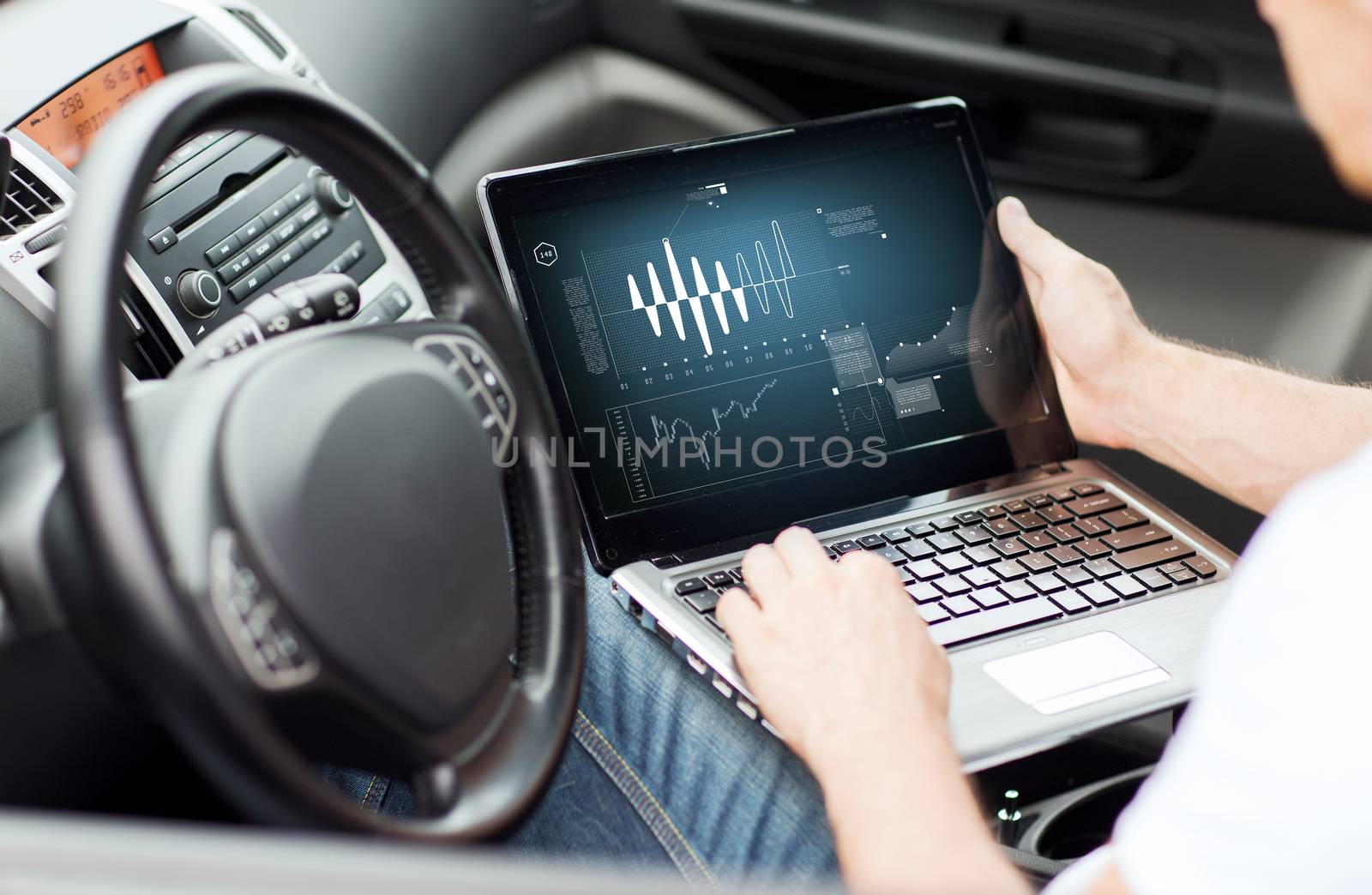 man using laptop computer in car by dolgachov