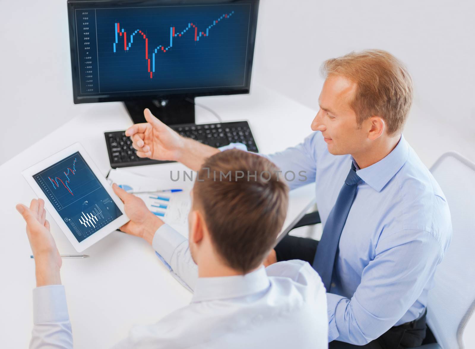 business, money and office concept - businessmen with notebook and tablet pc discussing forex chart on meeting