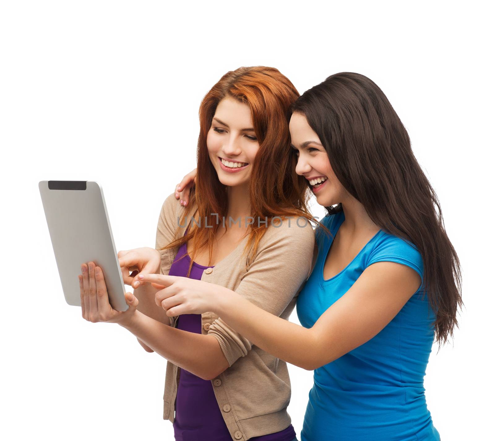 technology, friendship and people concept - two smiling teenagers pointing finger at tablet pc screen