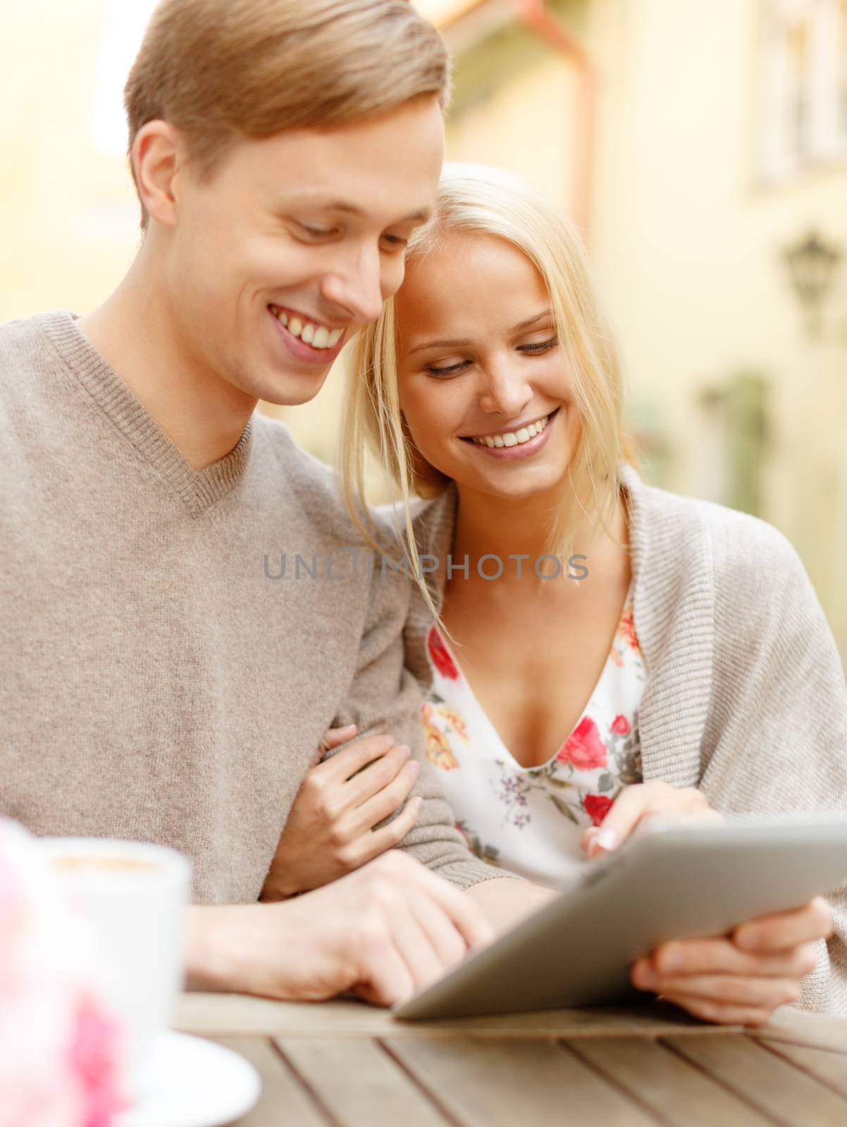 smiling couple with tablet pc computer in cafe by dolgachov