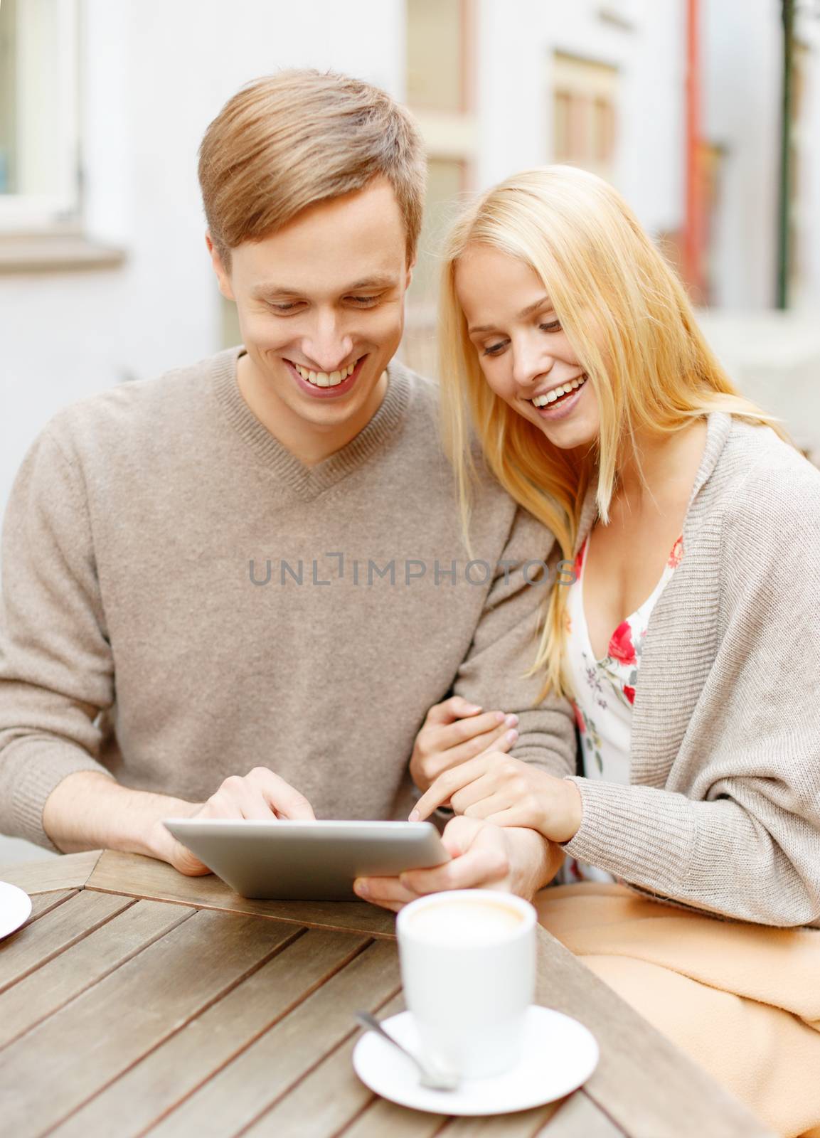 summer holidays, dating and technology concept - couple looking at tablet pc in cafe in the city