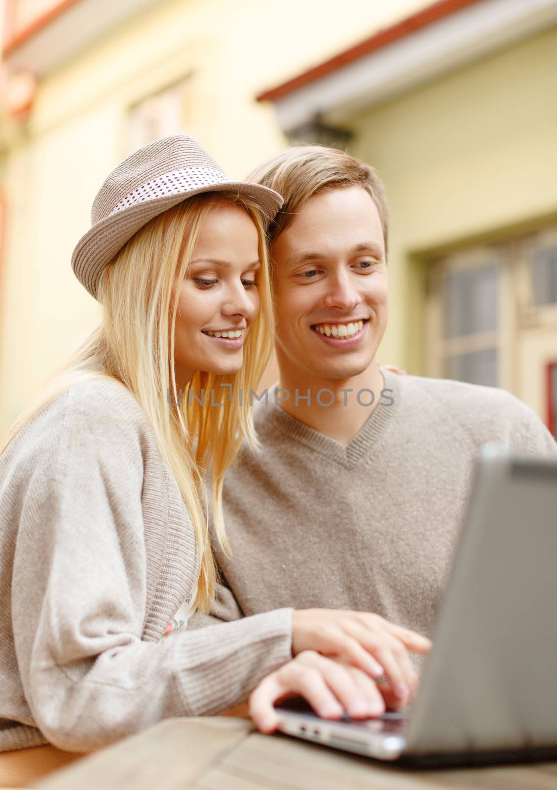 summer holidays, city, dating and technology concept - smiling couple with laptop computer in cafe