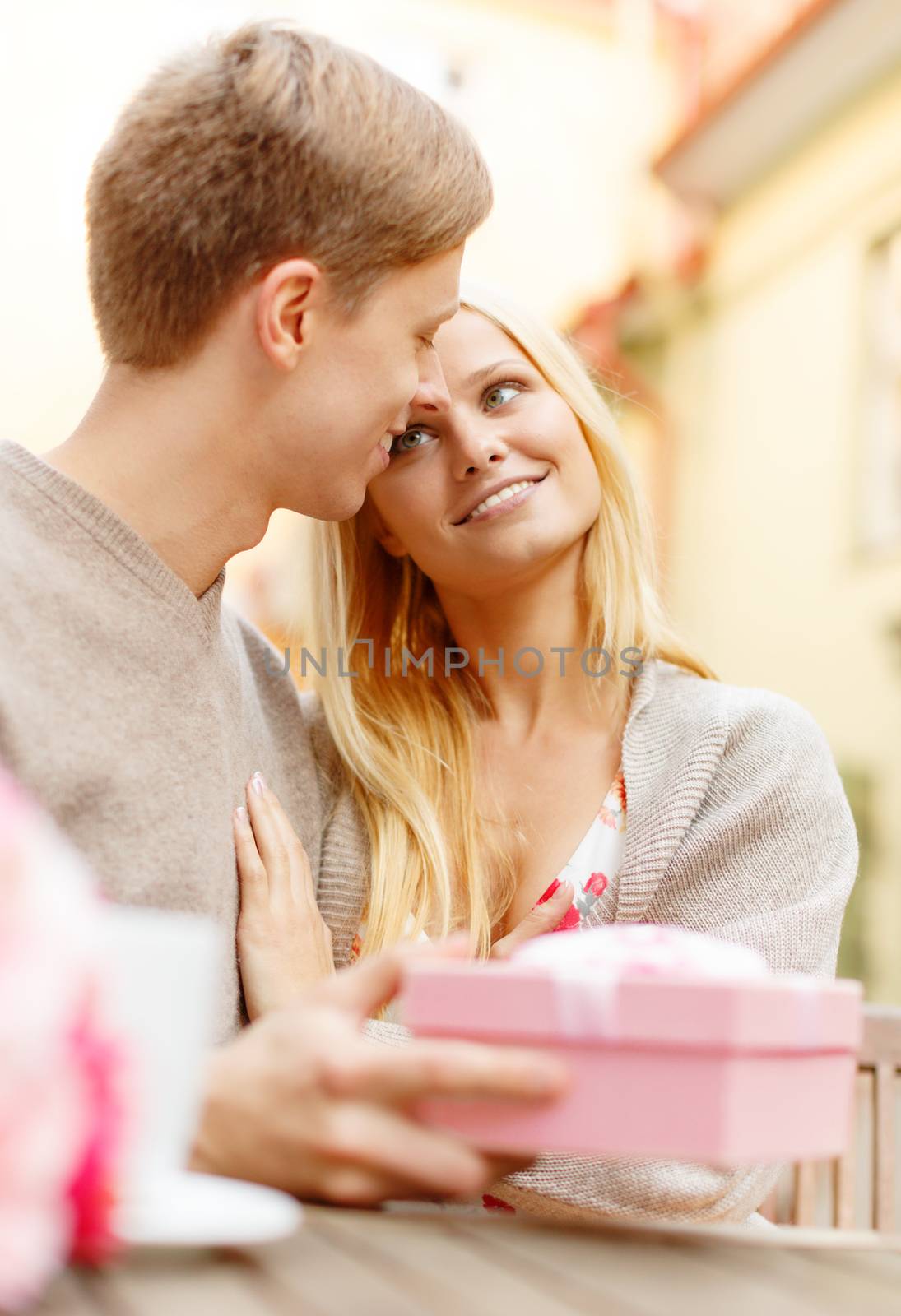 summer holidays, love, travel, tourism, relationship and dating concept - romantic happy couple with gift in the cafe