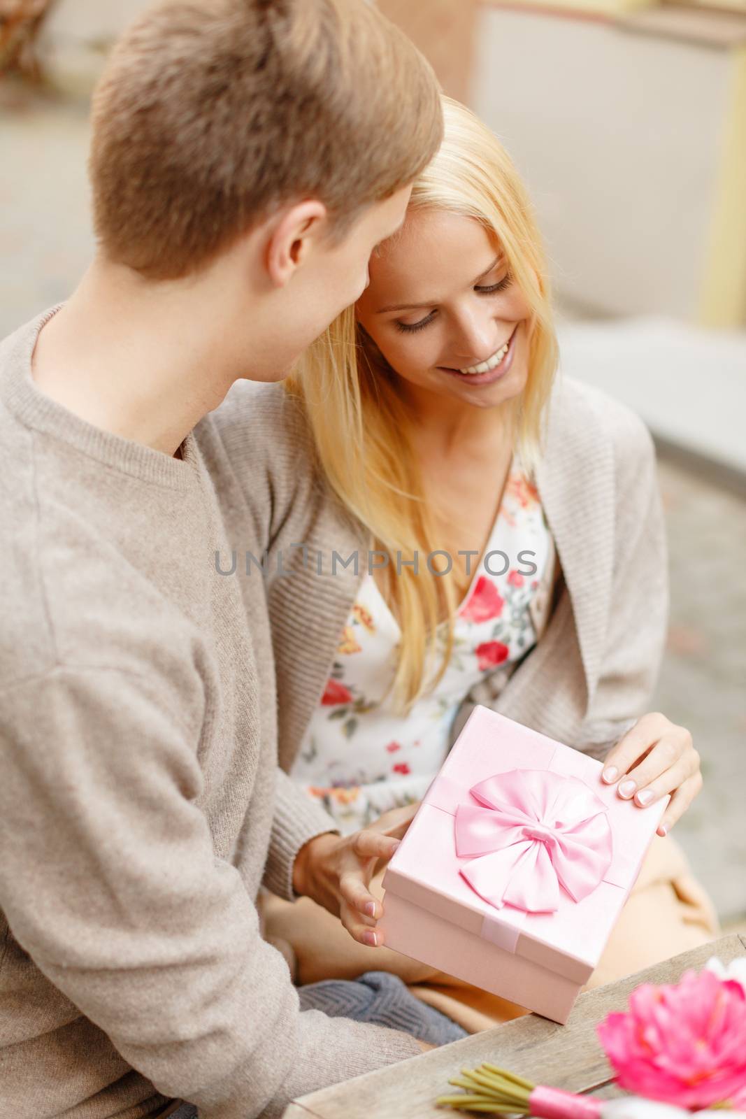 romantic happy couple with gift in the cafe by dolgachov