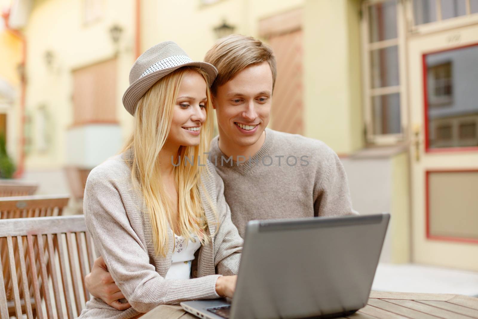 smiling couple with laptop computer in cafe by dolgachov