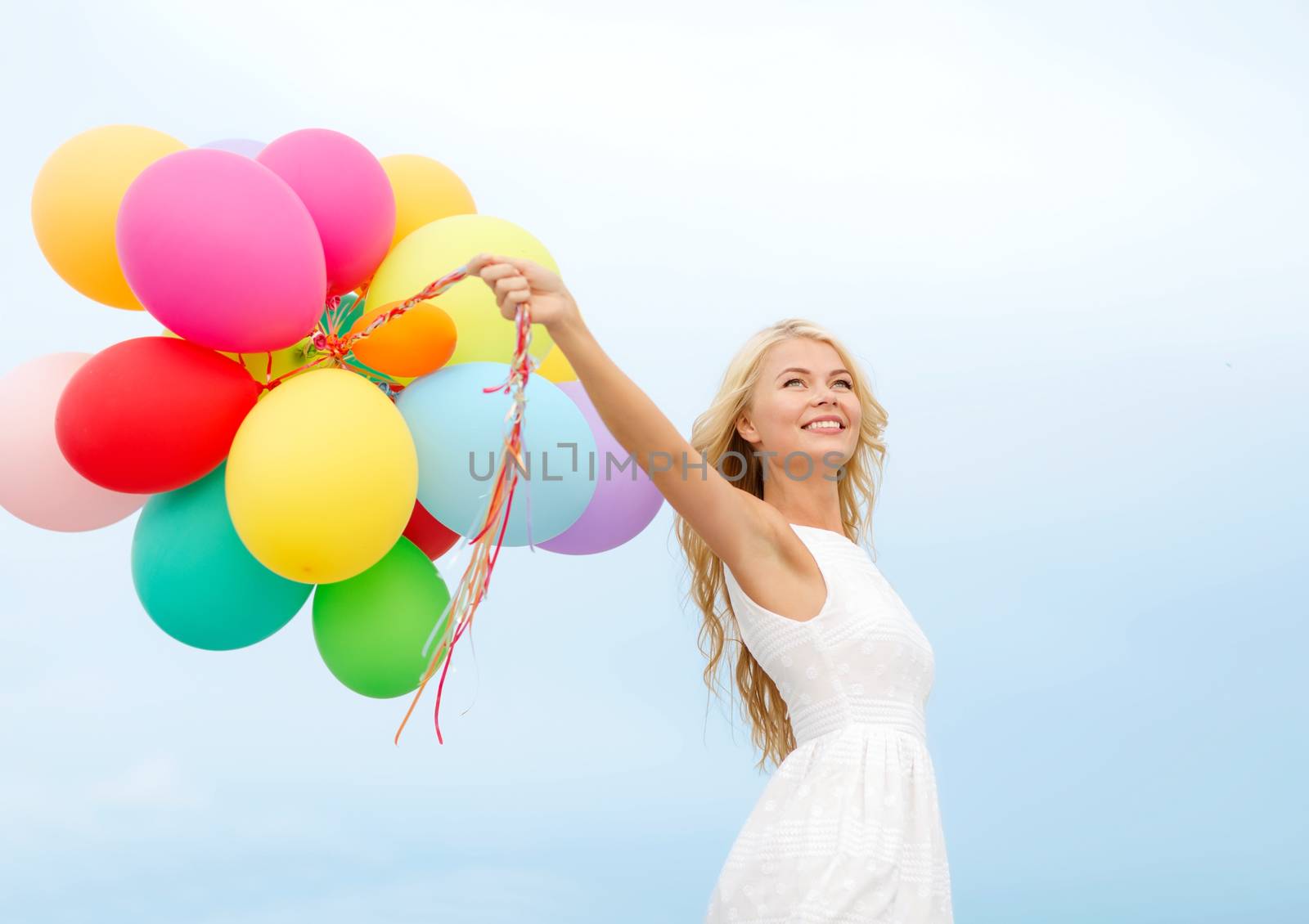 smiling woman with colorful balloons outside by dolgachov