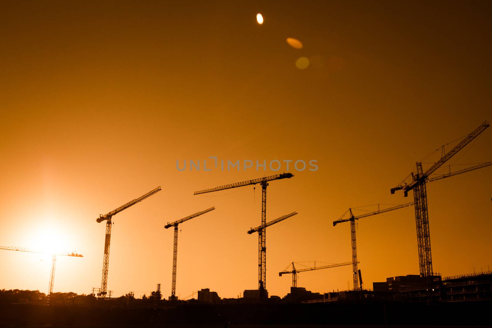 Crane Silhouette of a big Construction Site in the Evening