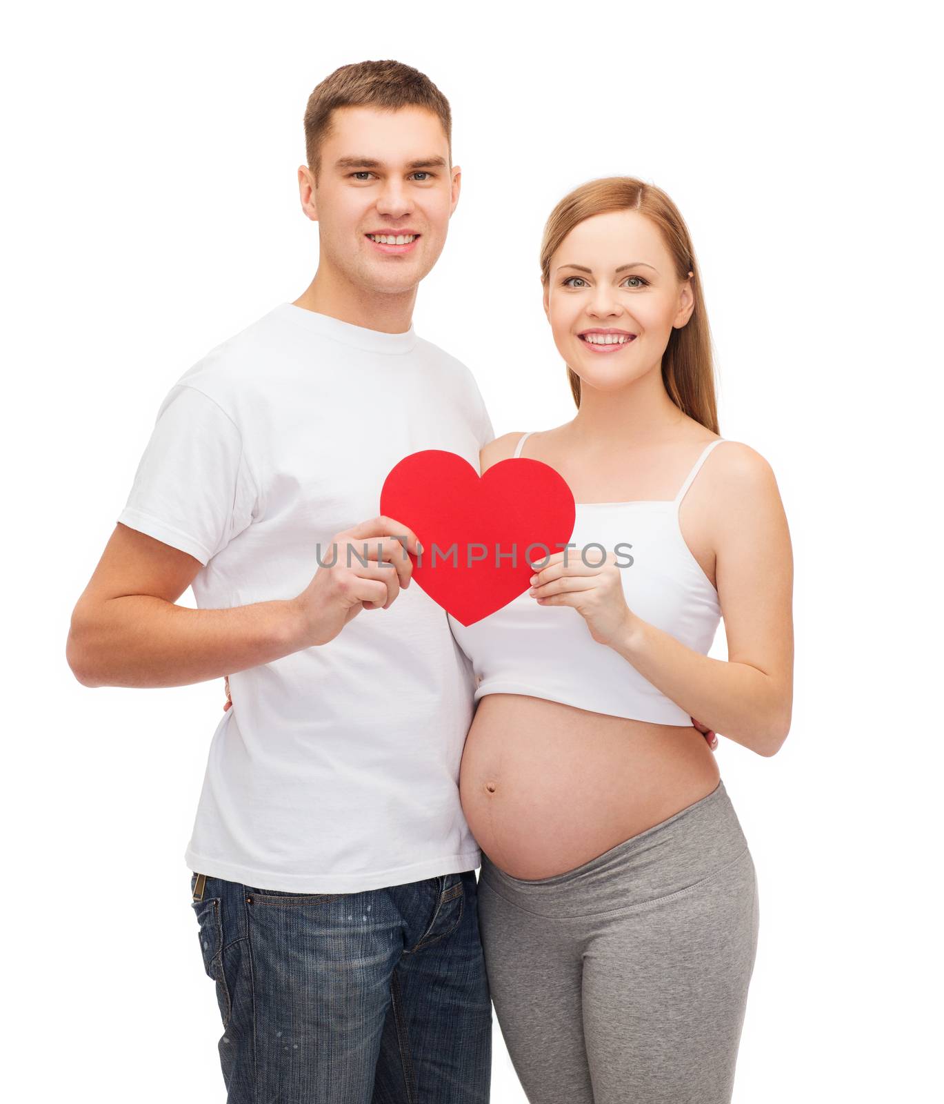 pregnancy, parenthood, love and happiness concept - happy young family expecting child with big red heart