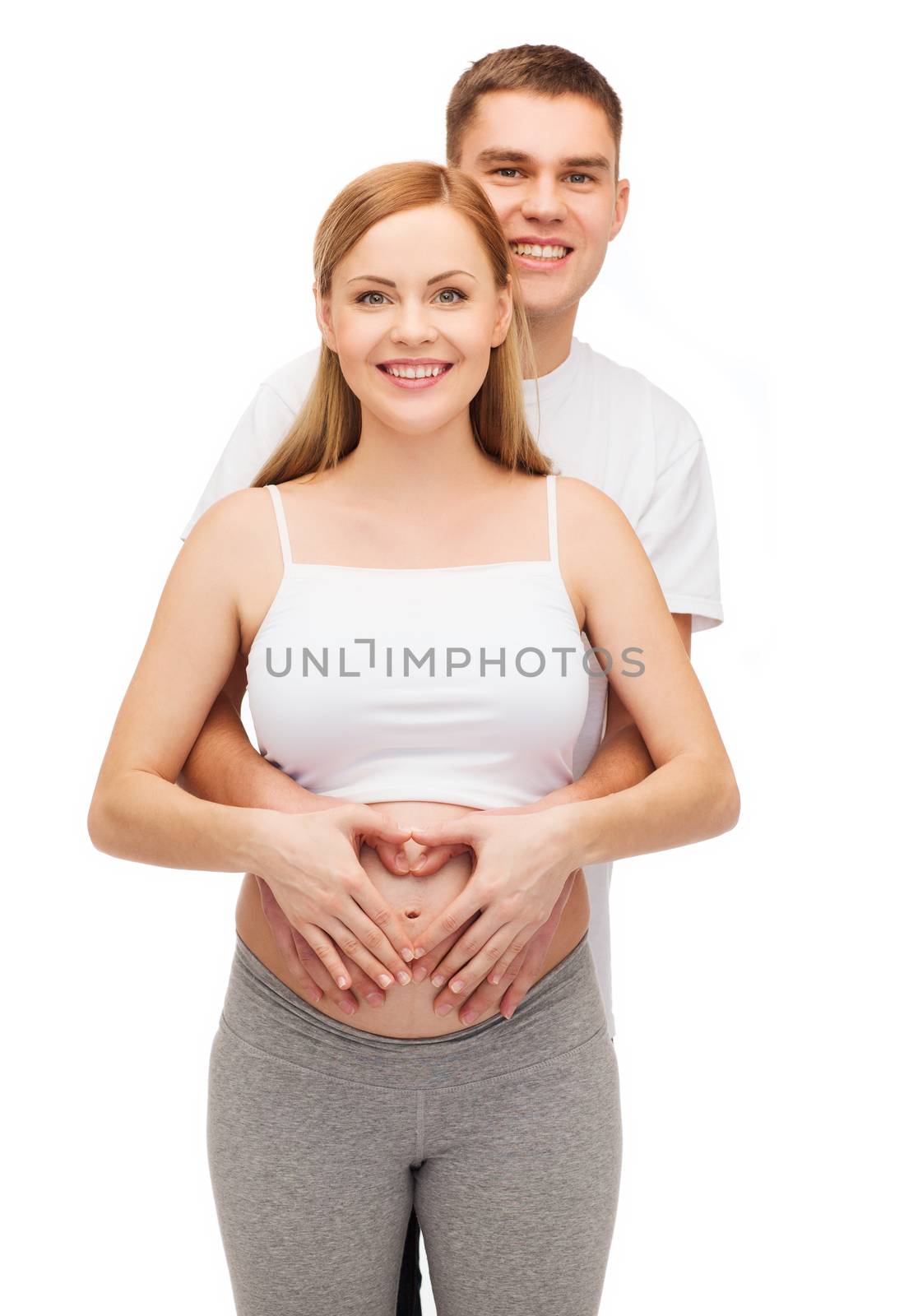 pregnancy, parenthood, love and happiness concept - happy young family expecting child showing heart with hands