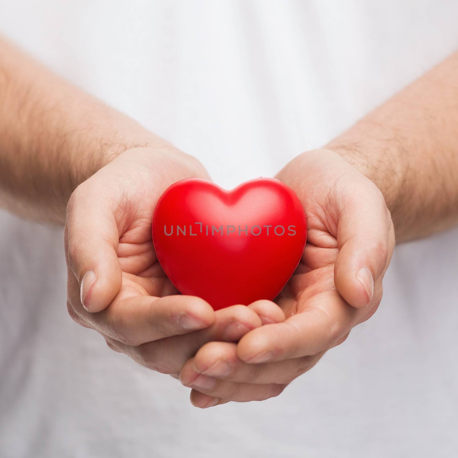 people, relationship and love concept - close up of mans cupped hands showing red heart