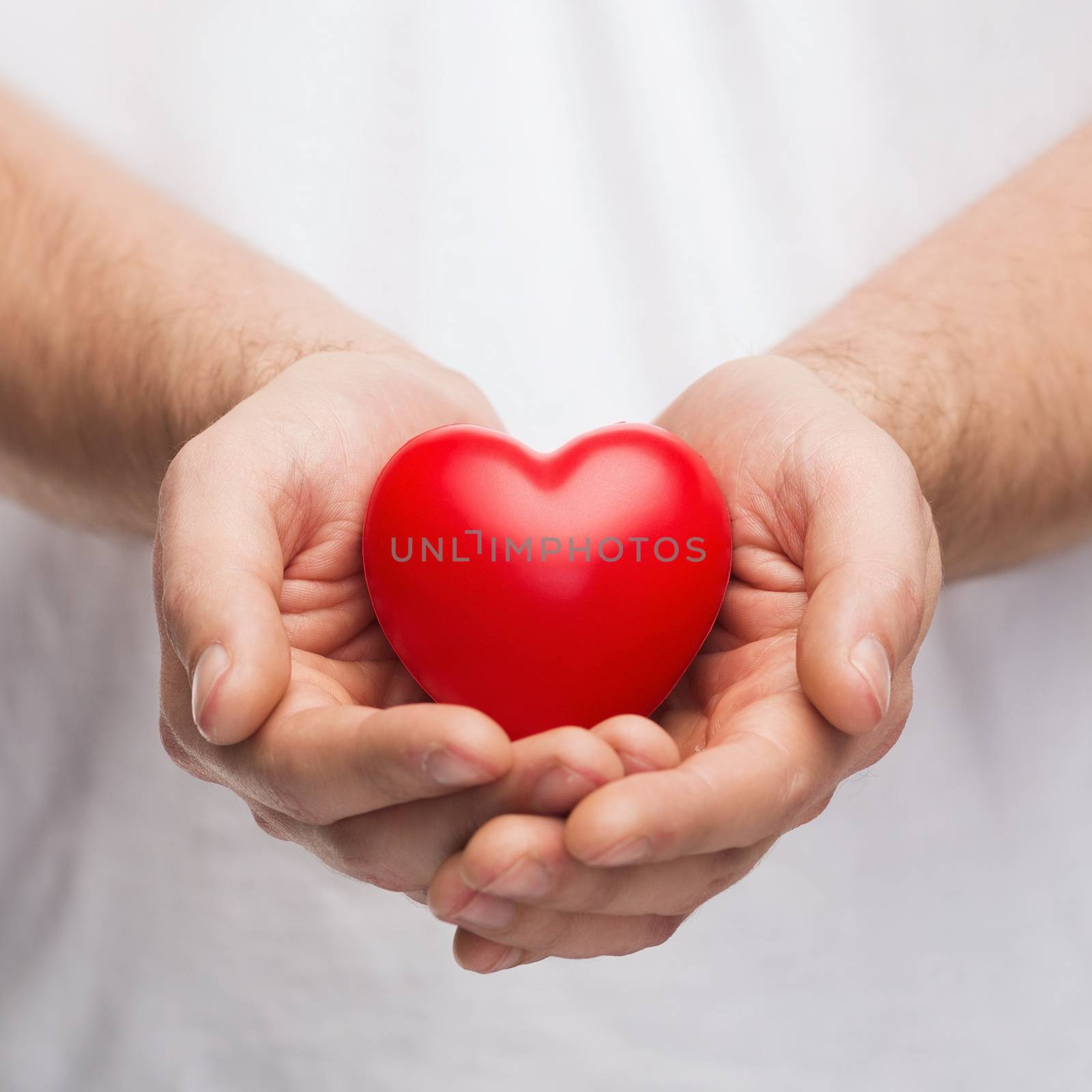 mans cupped hands showing red heart by dolgachov