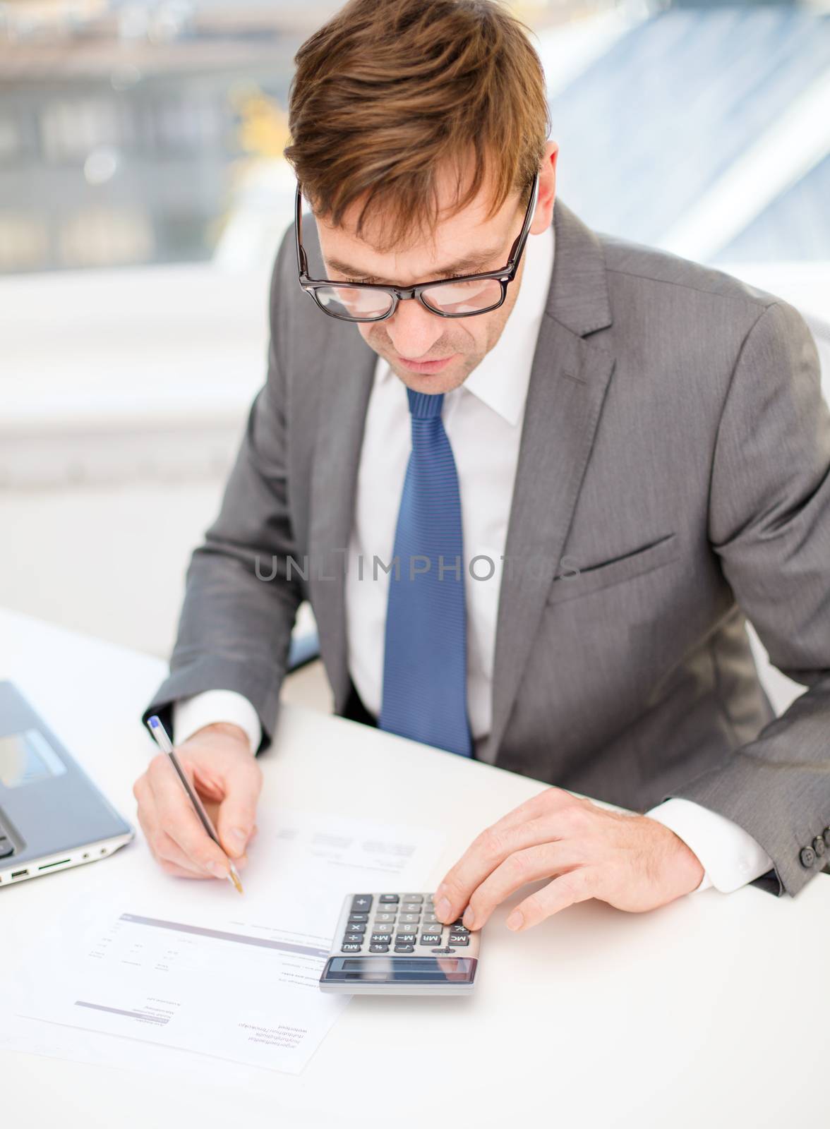 business, office, school and education concept - businessman with laptop computer, papers and calculator