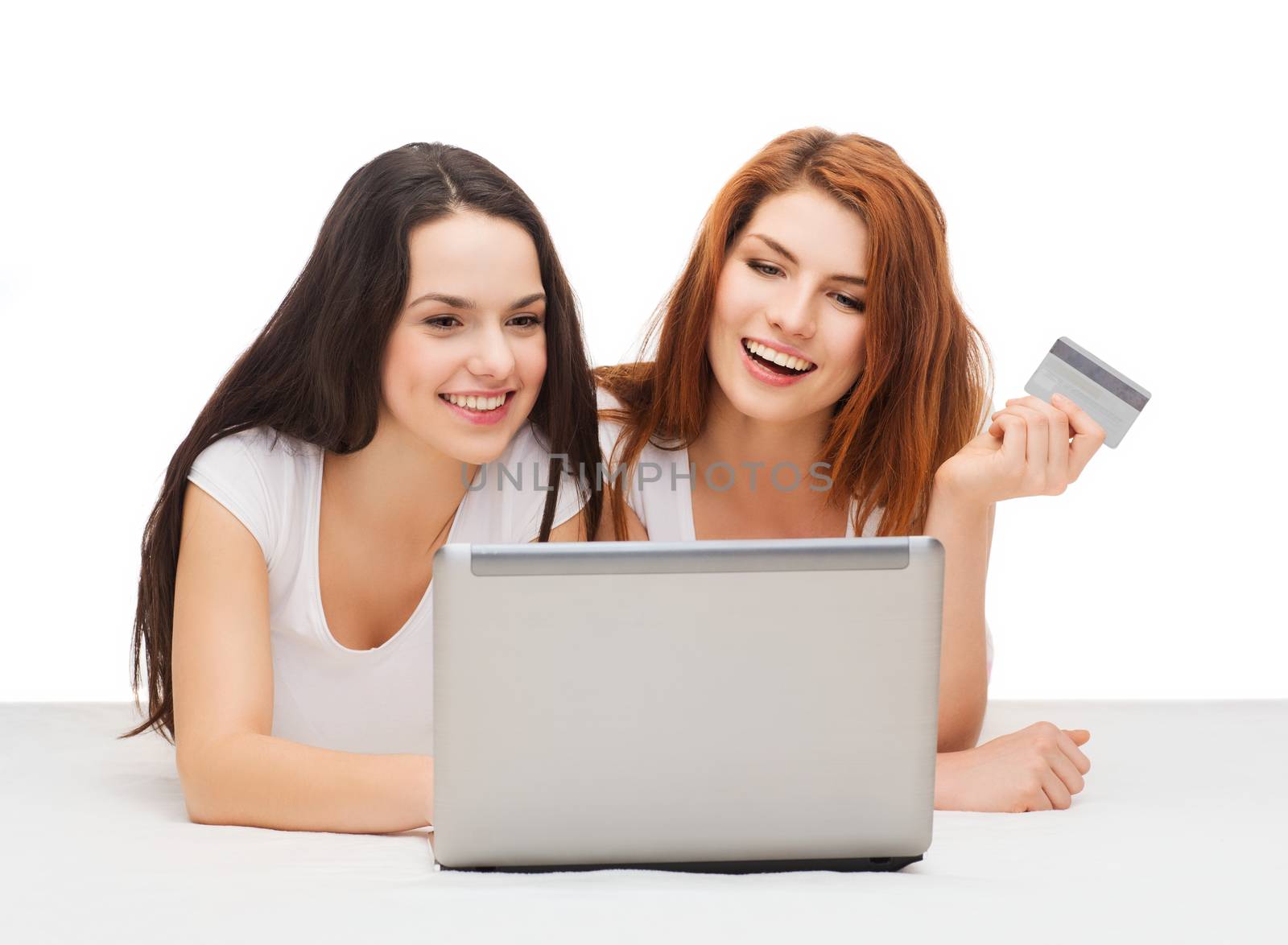 online shopping and technology concept - two smiling teenage girls with laptop computer and credit card