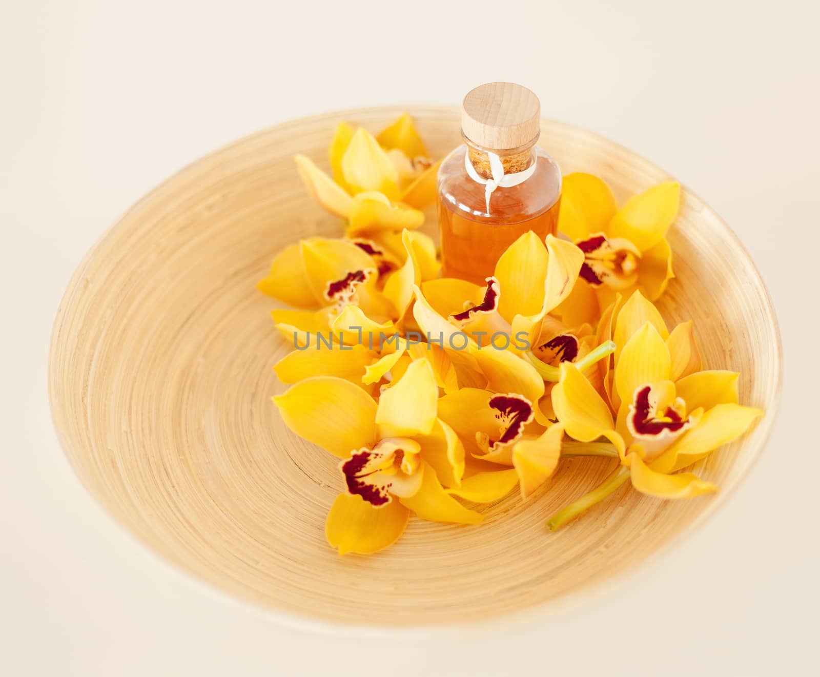 closeup of wooden bowl with orchids and oil by dolgachov