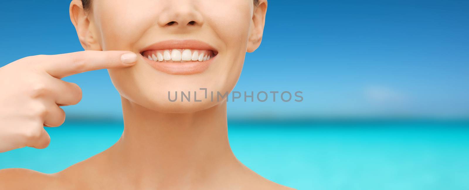 beauty and dental health concept - closeup picture of beautiful woman pointing finger to her teeth