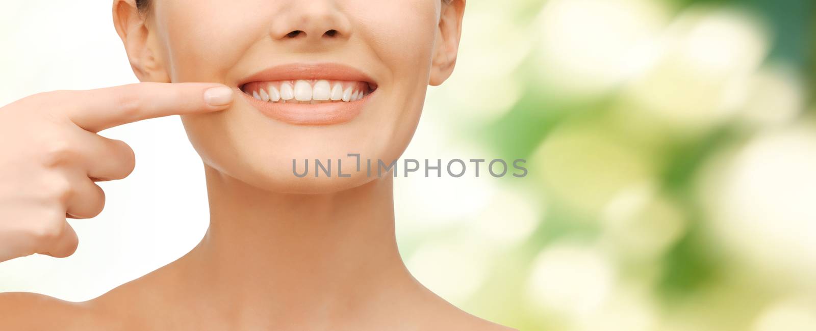 beauty and dental health concept - closeup picture of beautiful woman pointing finger to her teeth