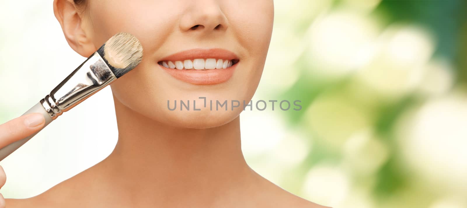 beauty amd make-up concept - closeup picture of beautiful woman with brush applying cream foundation