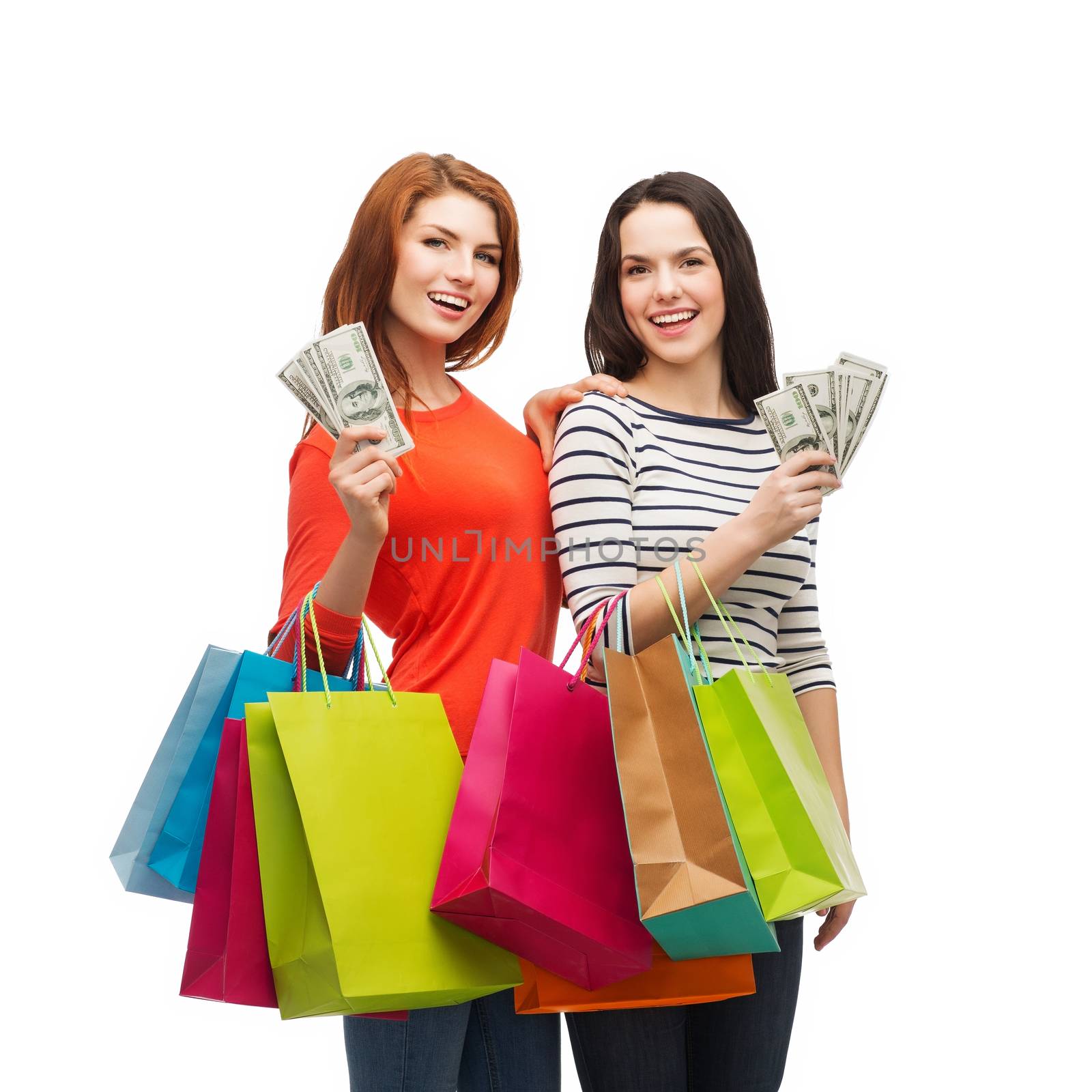 smiling teenage girls with shopping bags and money by dolgachov