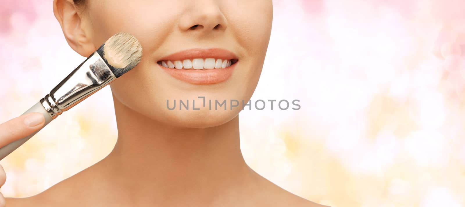 beauty amd make-up concept - closeup picture of beautiful woman with brush applying cream foundation