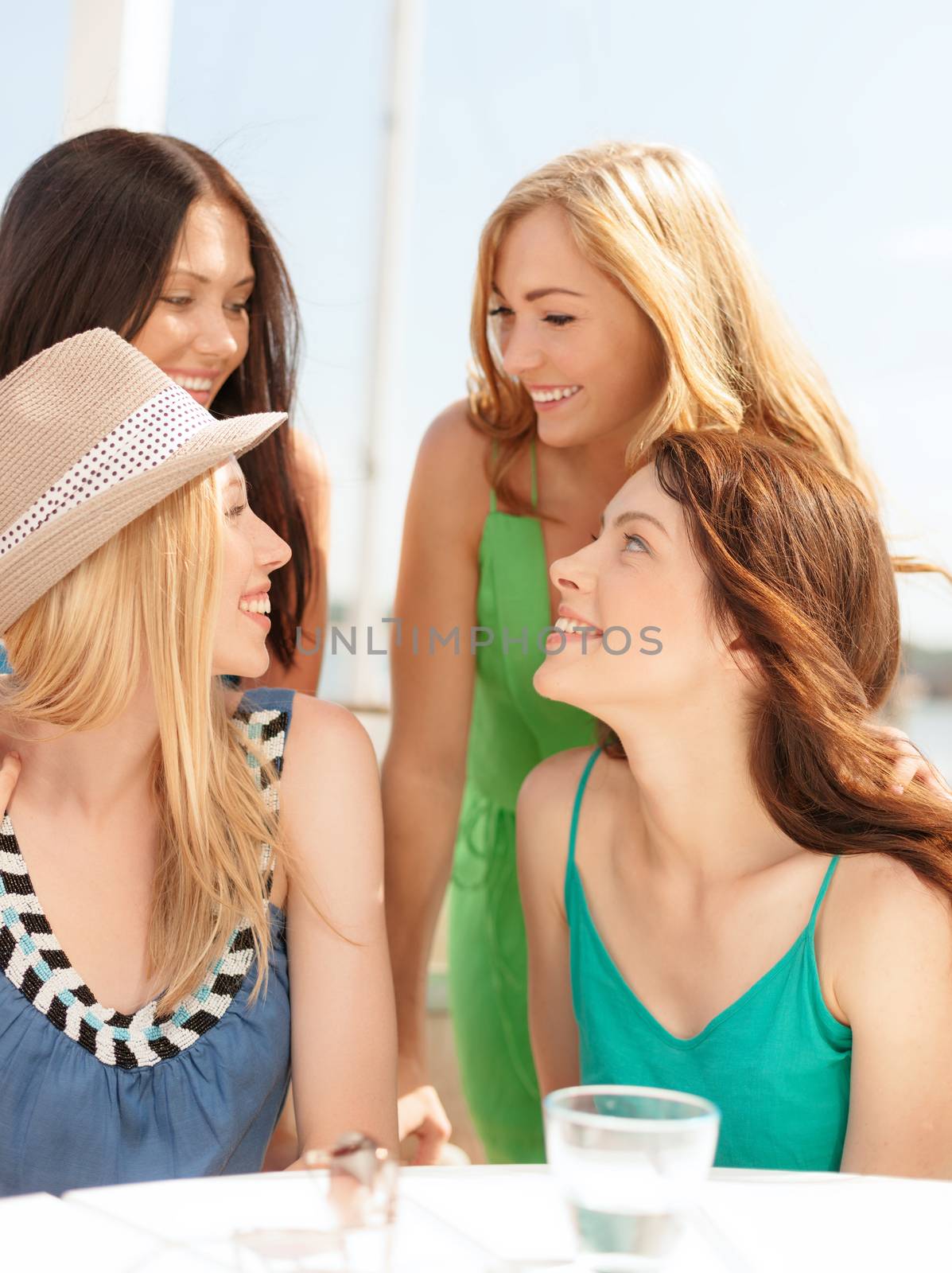 group of smiling girls in cafe on the beach by dolgachov