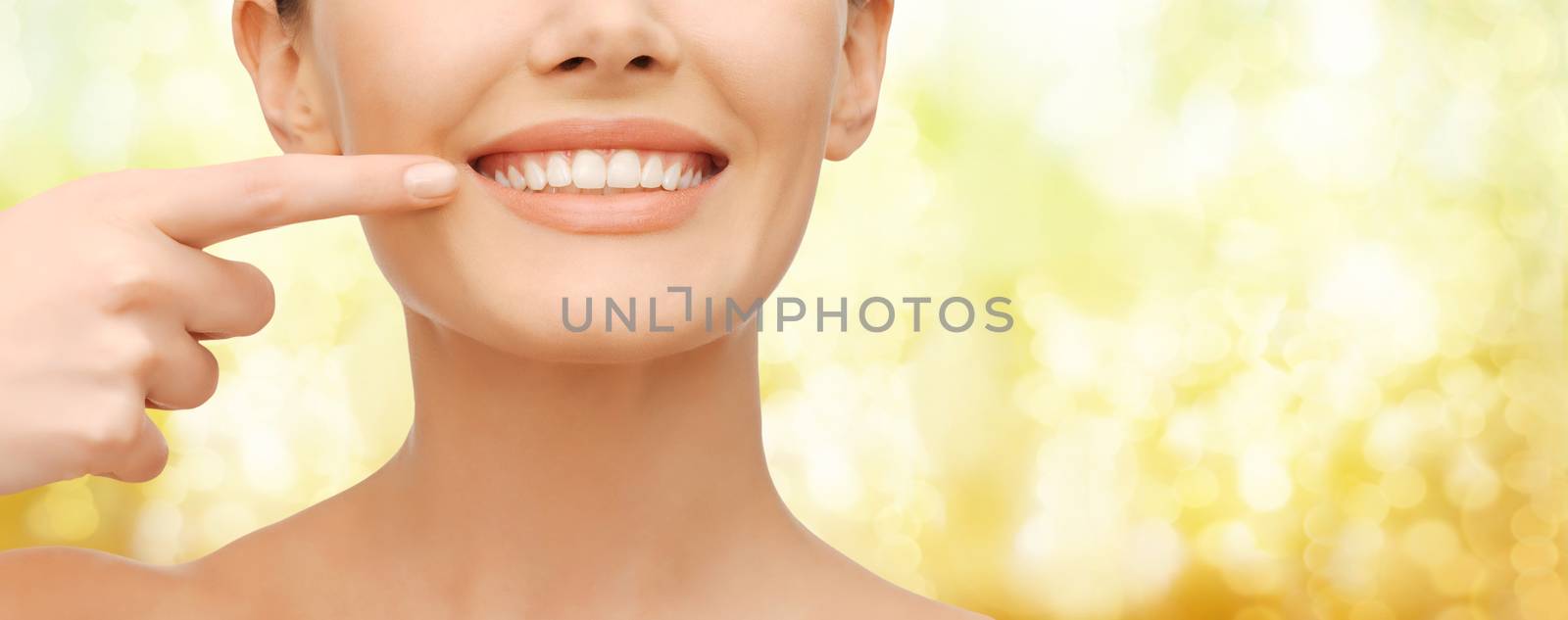 beauty and dental health concept - closeup picture of beautiful woman pointing finger to her teeth