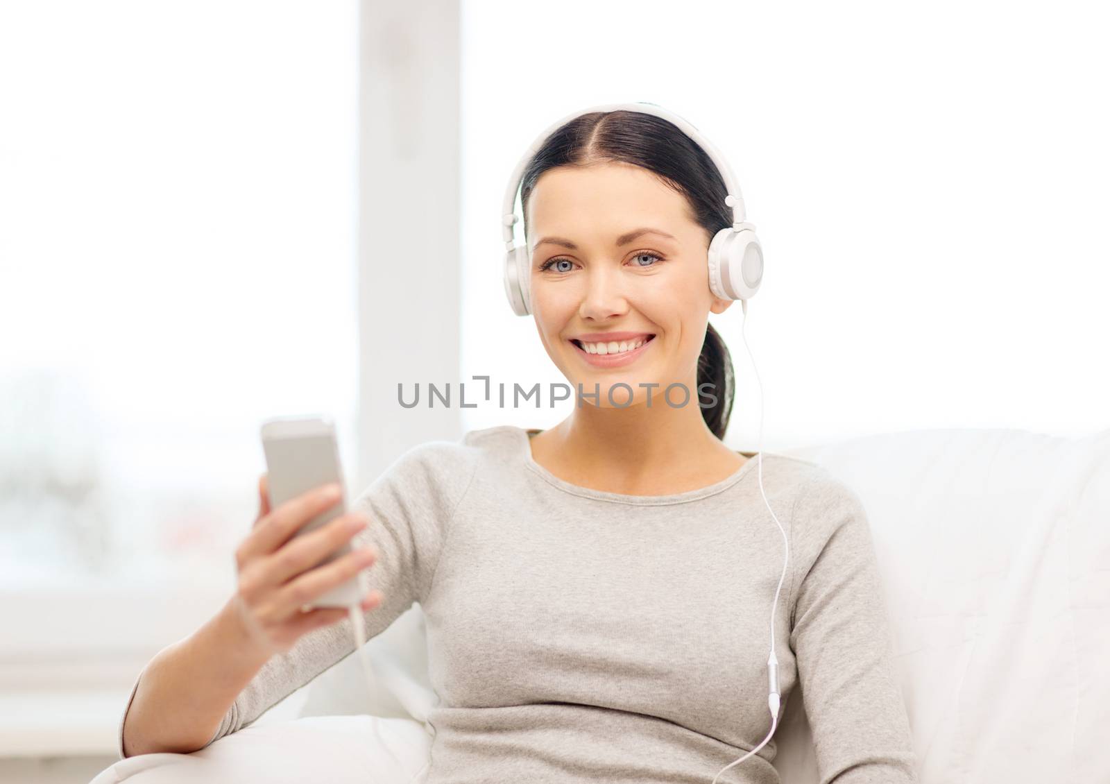 woman with smartphone and headphones at home by dolgachov