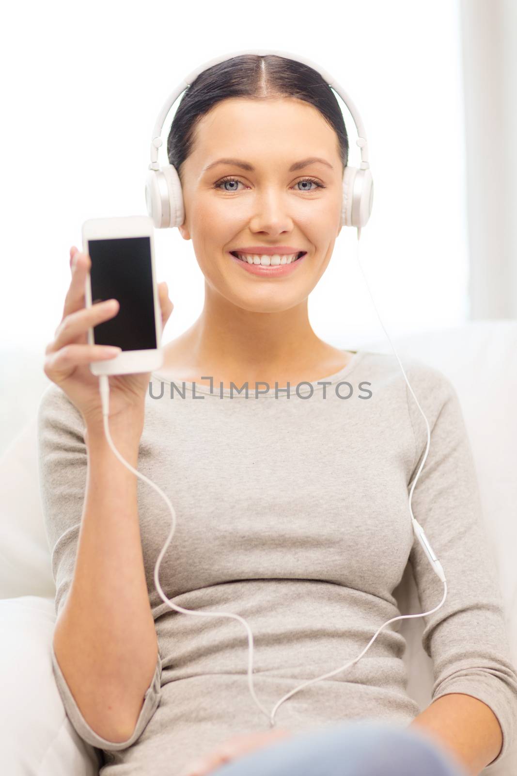 woman with smartphone and headphones at home by dolgachov