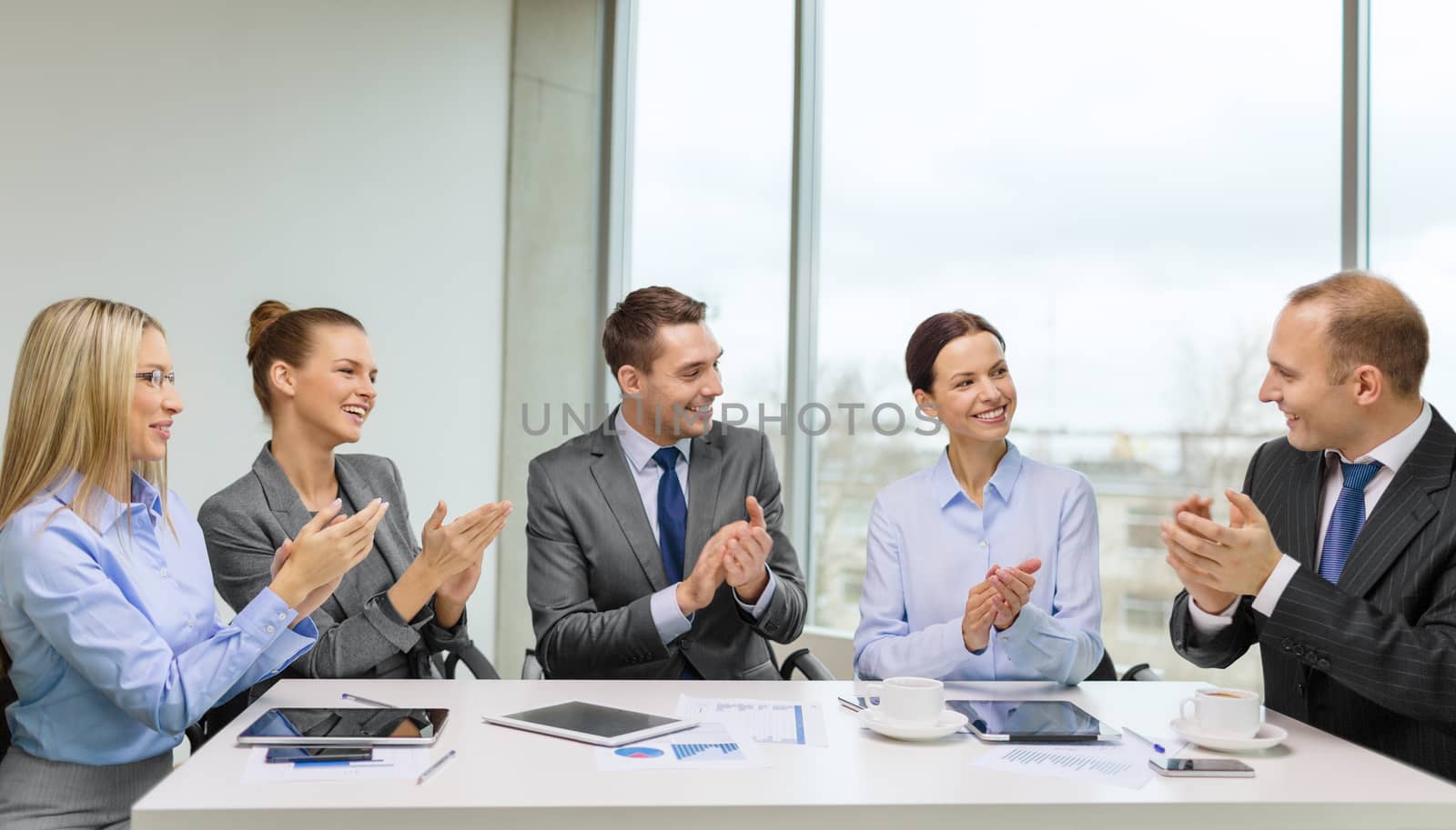 business, technology and office concept - happy business team with laptop computers, documents and coffee clapping hand