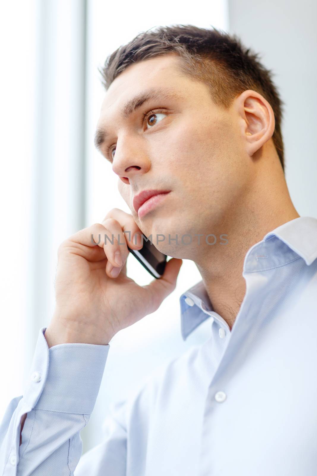 business, technology and office concept - serious businessman with smartphone