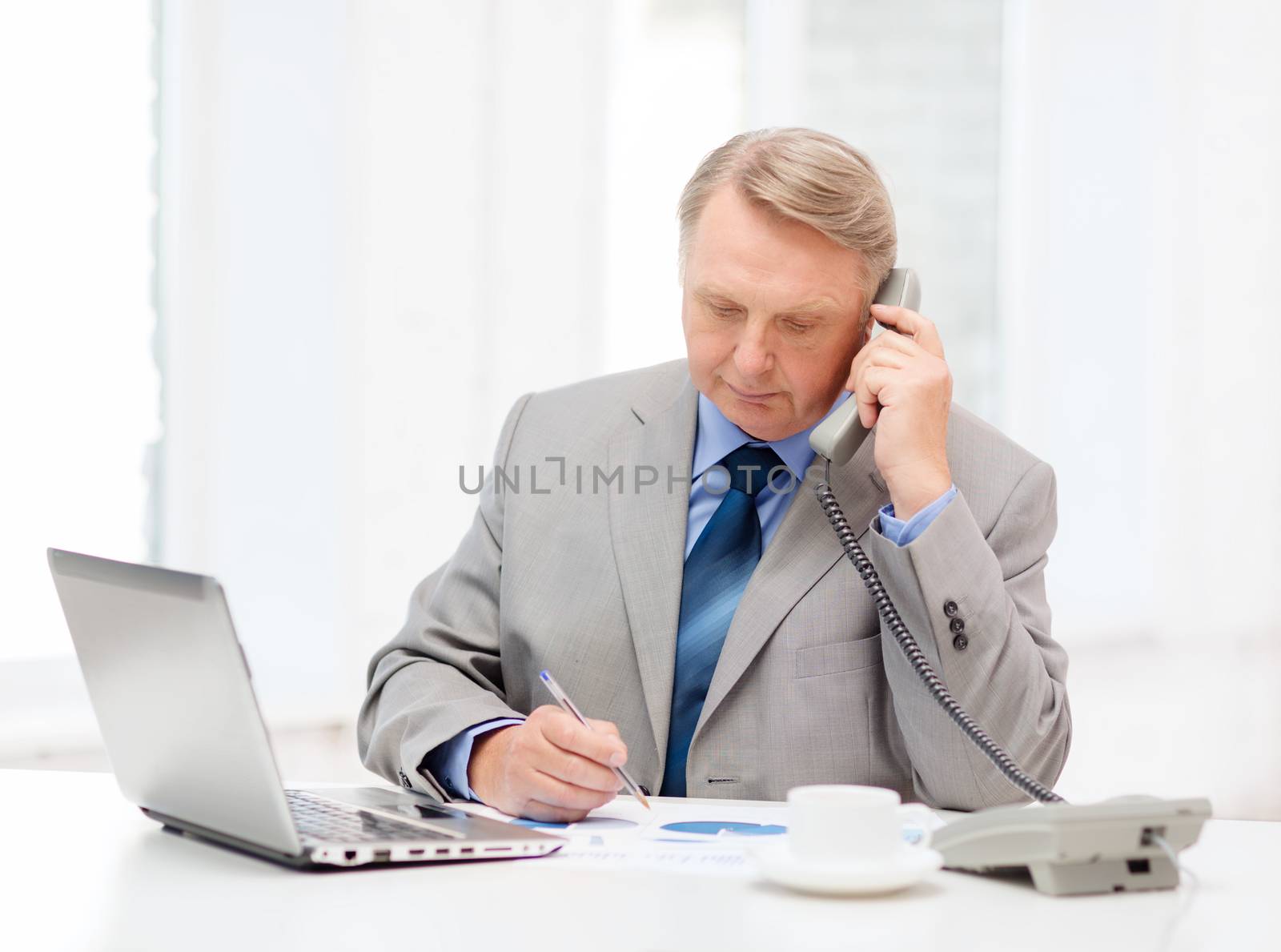busy older businessman with laptop and telephone by dolgachov