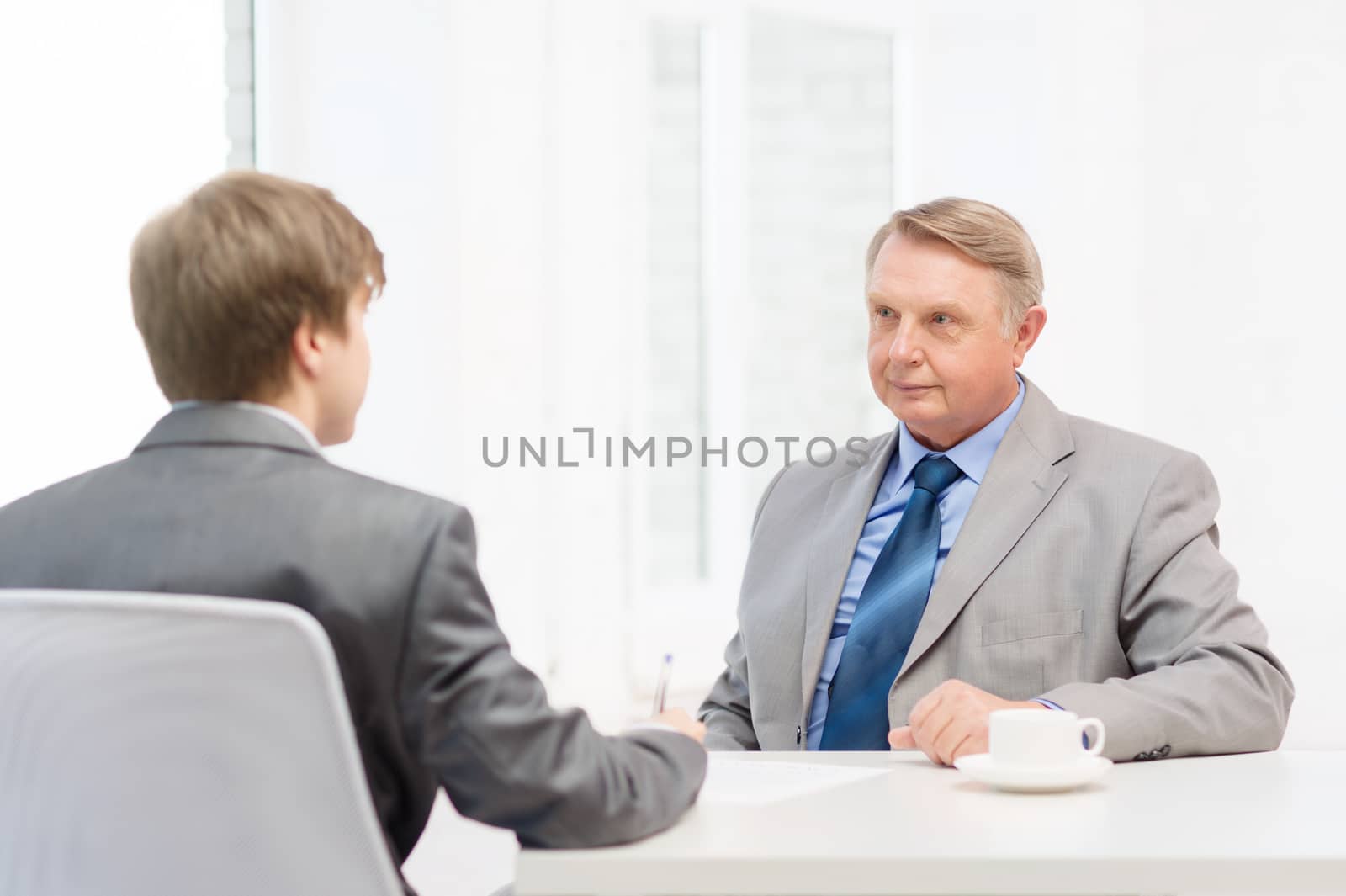 older man and young man signing papers in office by dolgachov