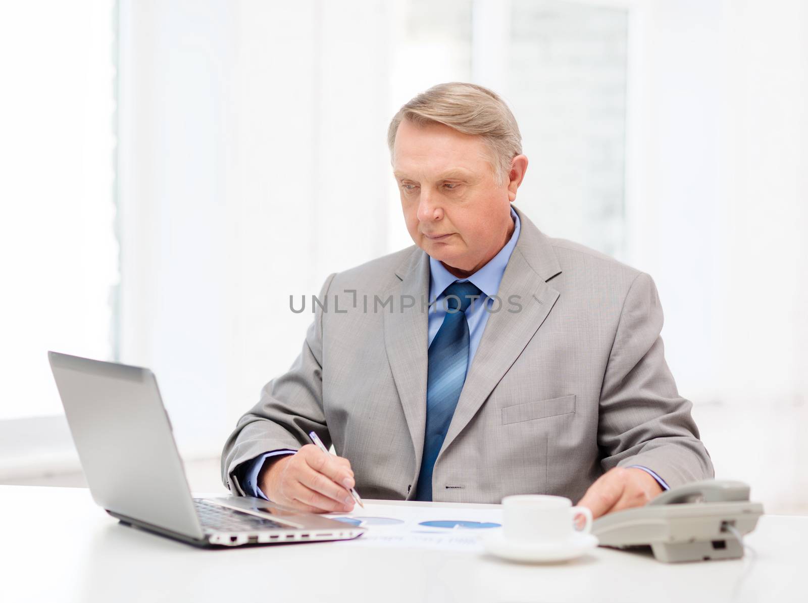 business, technologym communication and office concept - busy older businessman with laptop, charts, coffee and telephone in office