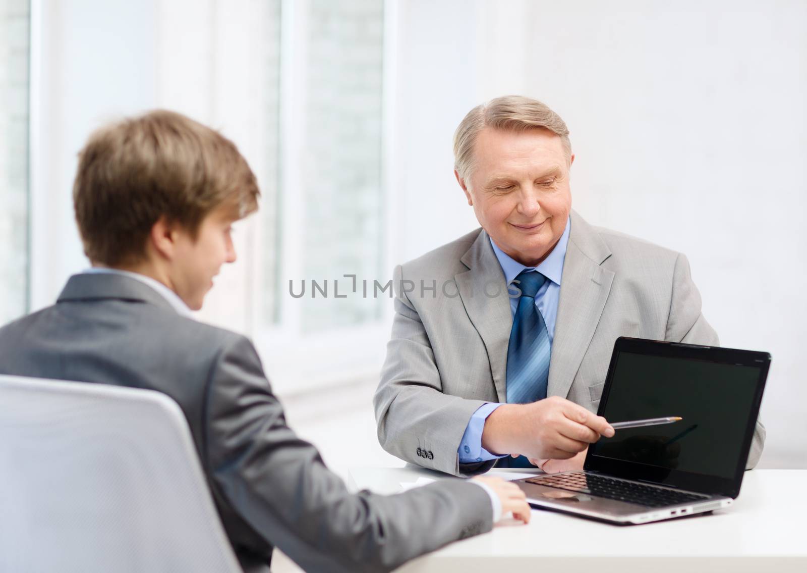 business, advertisement, technology and office concept - older man and young man with laptop computer in office