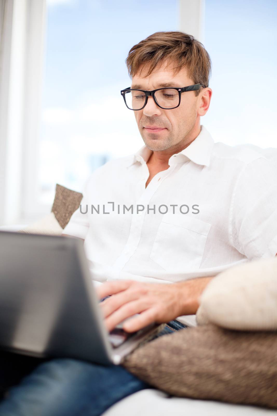 technology, business and lifestyle concept - man in eyeglasses working with laptop at home