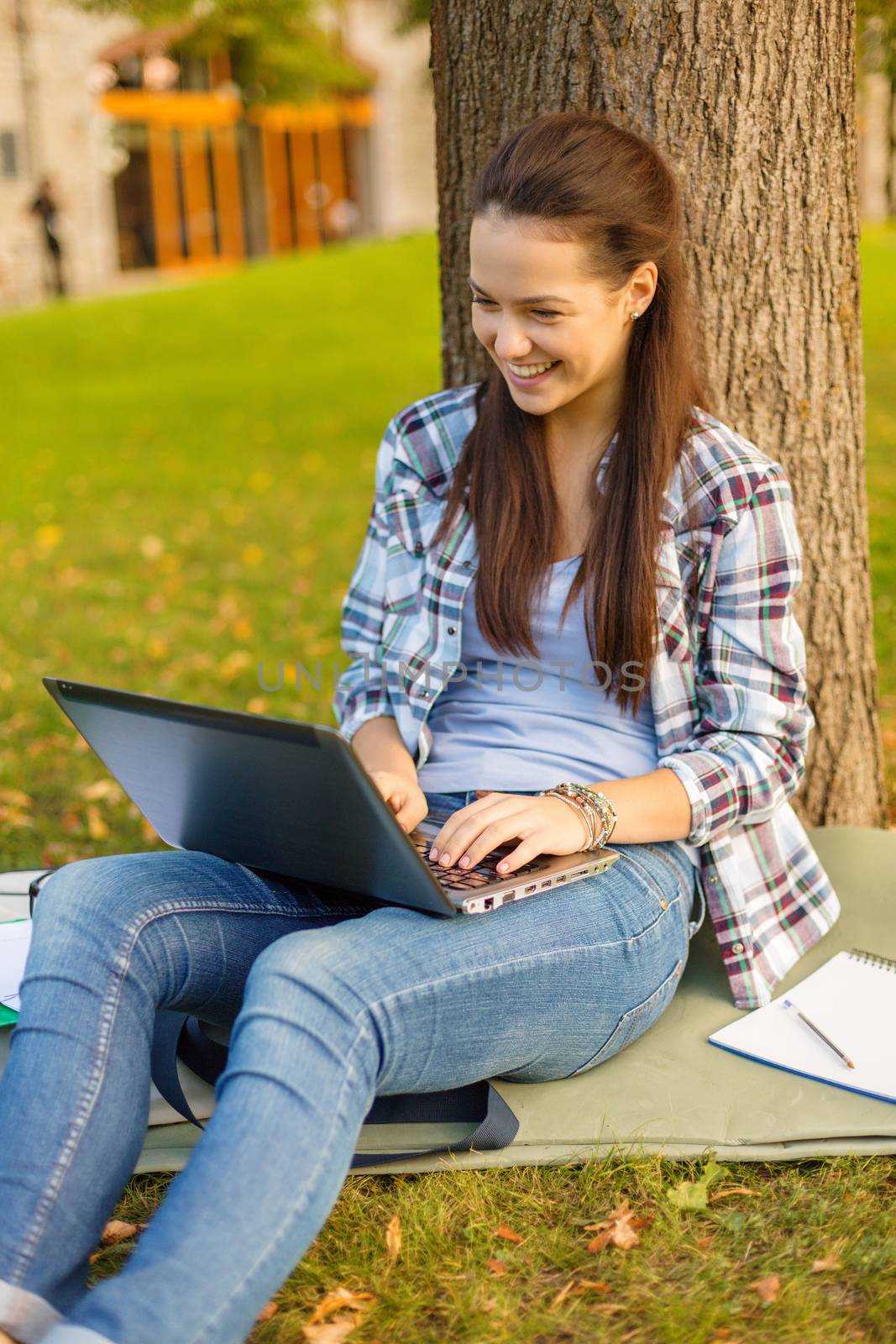 education, technology and internet concept - smiling teenager with laptop computer and notebook