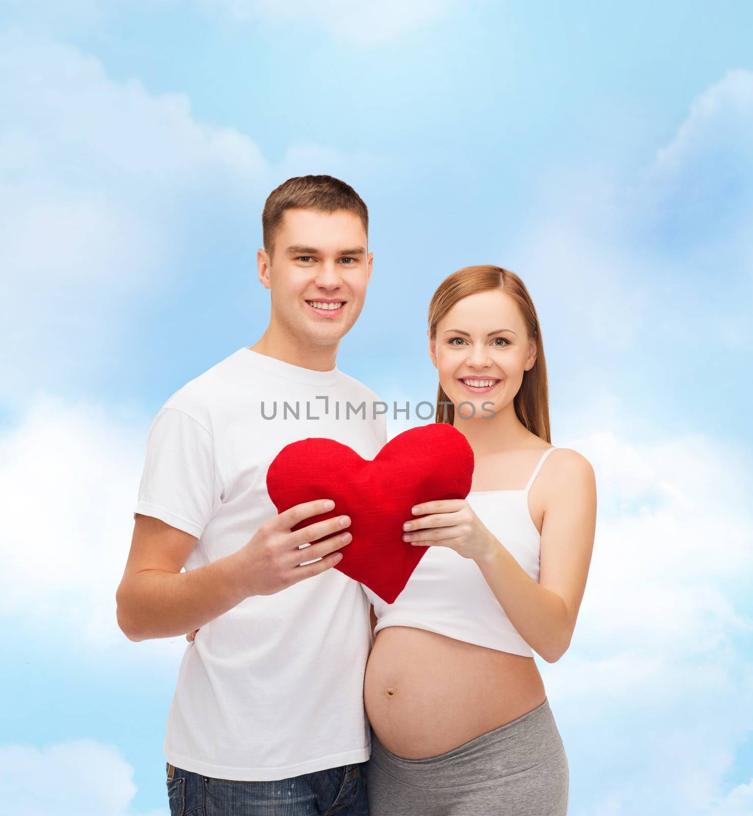 happy young family expecting child with big heart by dolgachov