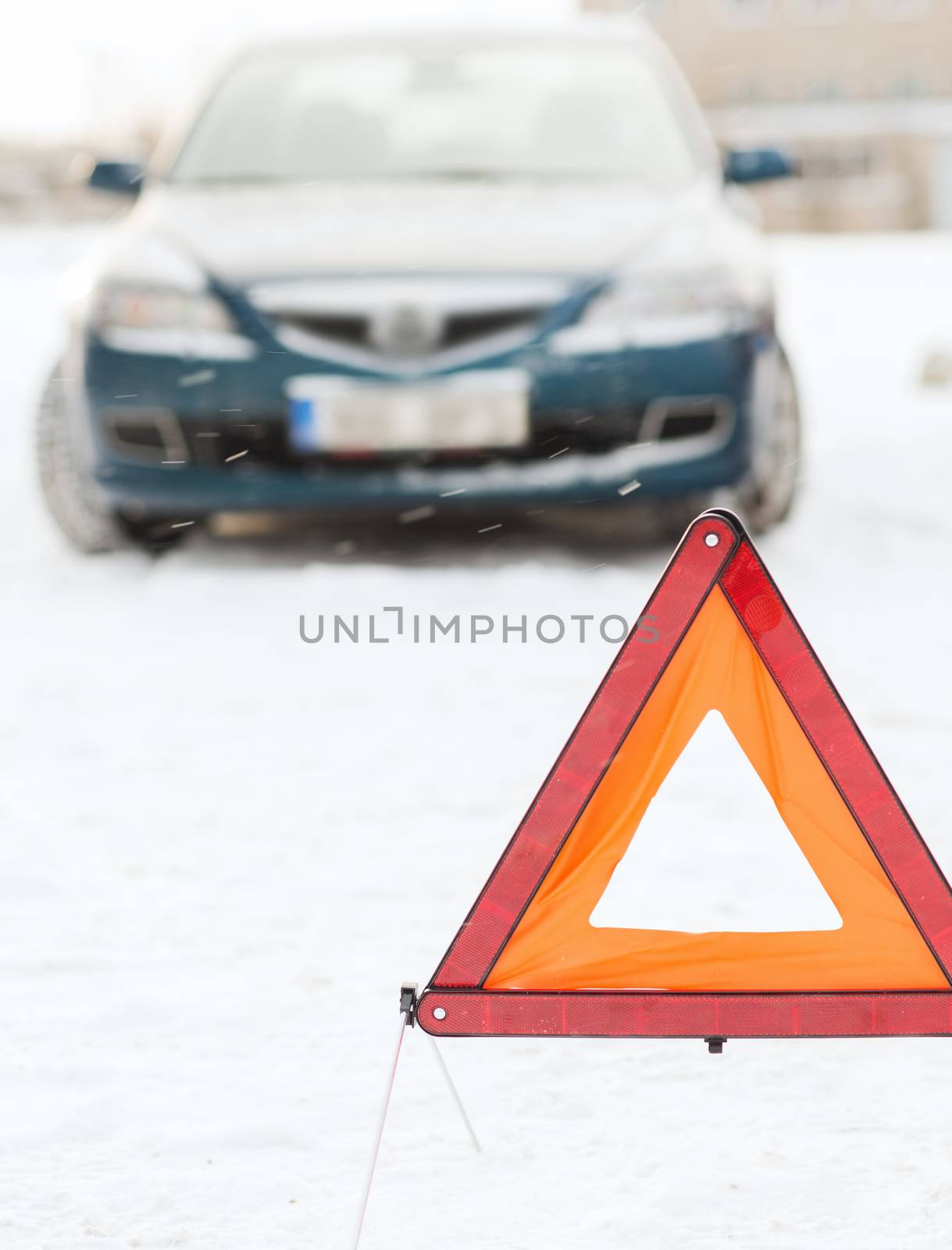 transportation, winter and vehicle concept - closeup of warning triangle and car