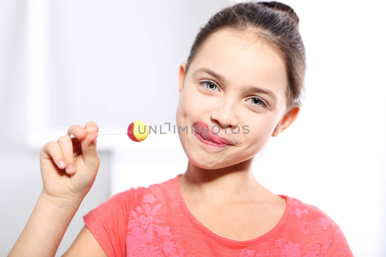 Young girl in a pink shirt with lollipop